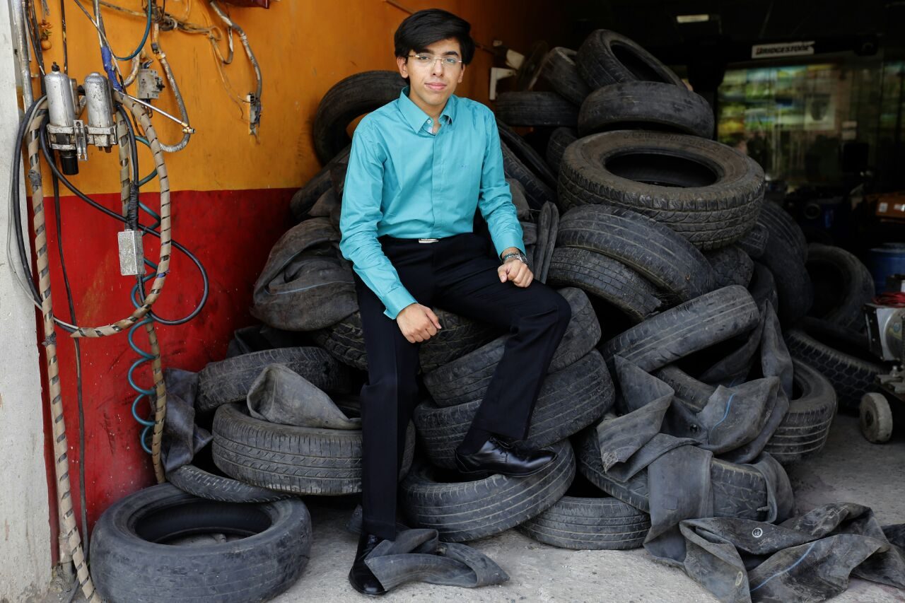 Anubhav Wadhwa sitting on a stack of end-of-life tyres in a tyre yard